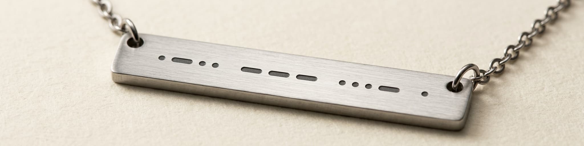 Close-up of the laser-engraved morse code dots and dashes on the steel bar